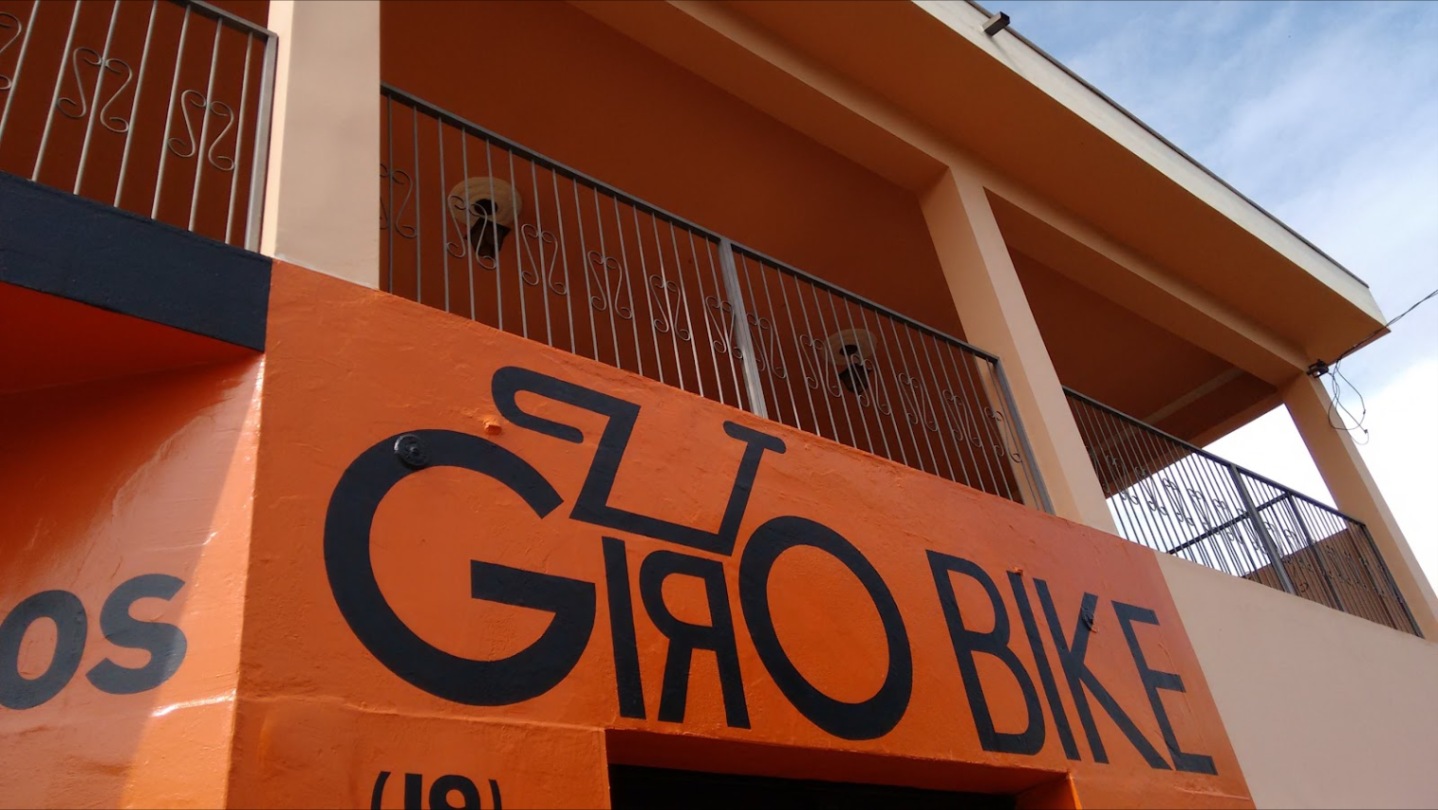 Fachada antiga da Giro Bike na Rua Alberto Santos Dumont, com o letreiro GIRO BIKE pintado em preto no sobrado laranja