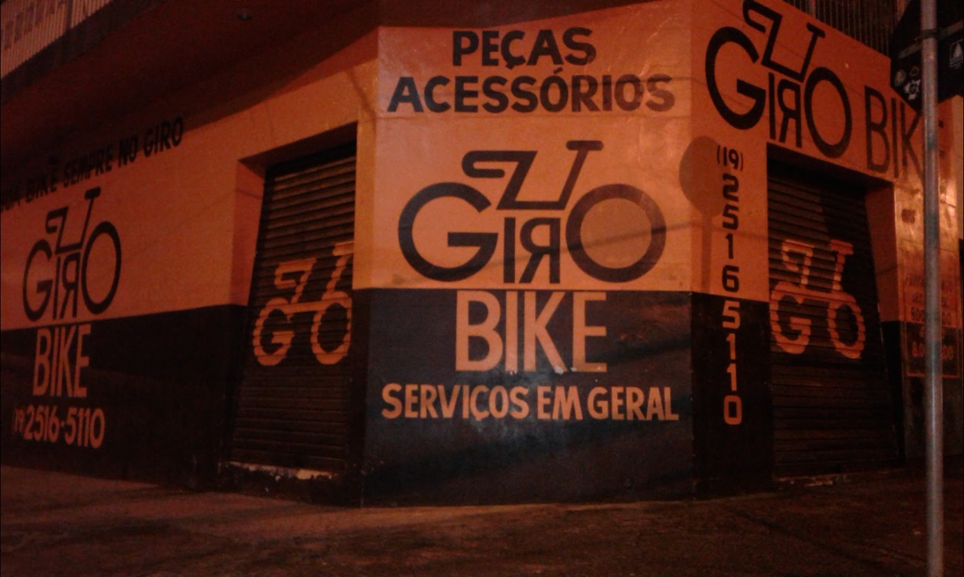 Esquina da antiga Giro Bike à noite, com peças, acessórios e serviços em geral pintados na parede