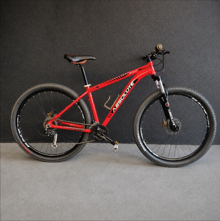 Mountain bike Absolute Wild aro 29 vermelha, encostada na parede grafite da Giro Bike