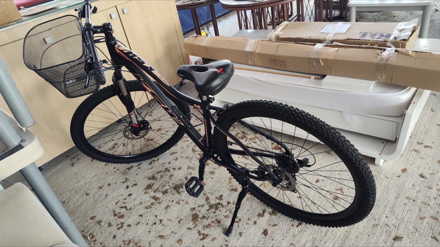 Mountain bike preta com cestinha instalada no guidão, dentro da loja